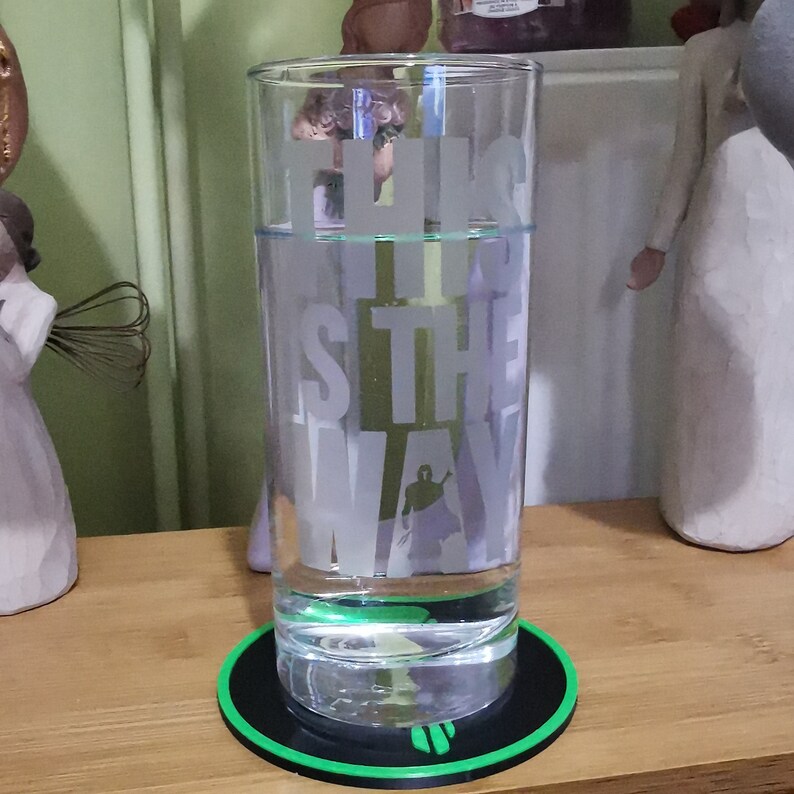 Puede incluir: Un vaso de vidrio transparente con el texto "This is the way" grabado en el lateral. El vaso est&aacute; lleno de agua y se encuentra sobre un posavasos redondo negro y verde.