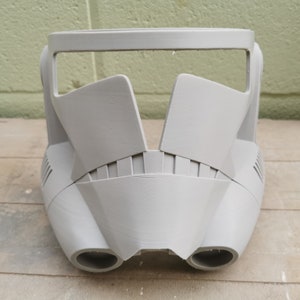 May include: A gray plastic helmet with a visor and two vents on the bottom. The helmet is designed to look like a Stormtrooper helmet from Star Wars.
