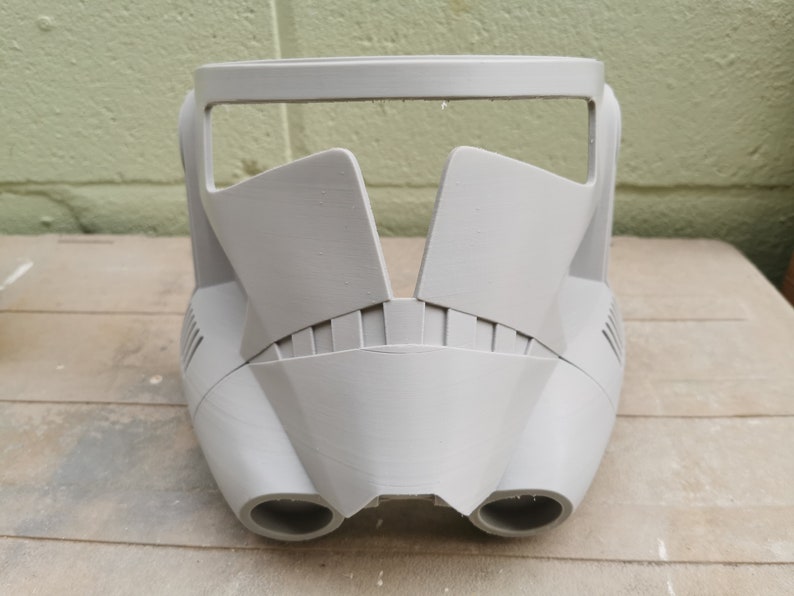 May include: A gray plastic helmet with a visor and two vents on the bottom. The helmet is designed to look like a Stormtrooper helmet from Star Wars.