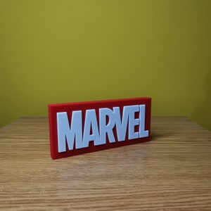 May include: A red rectangular sign with the word "MARVEL" in white raised letters.