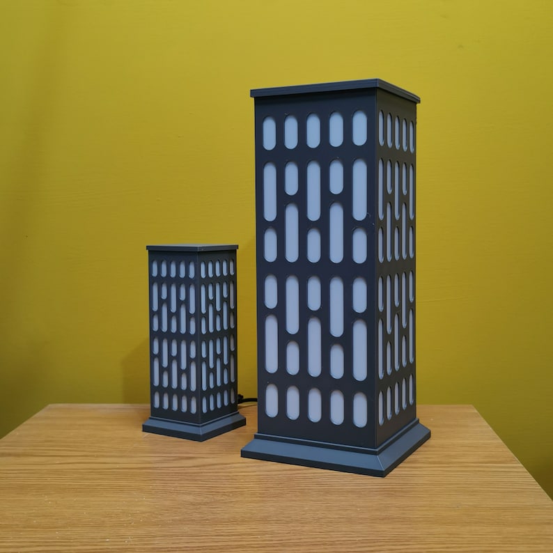 May include: Two gray table lamps with a geometric pattern. The larger lamp is taller than the smaller lamp.