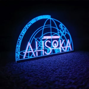 May include: A blue and pink neon sign with the text "STAR WARS" and "AHsoka" in a geometric design.
