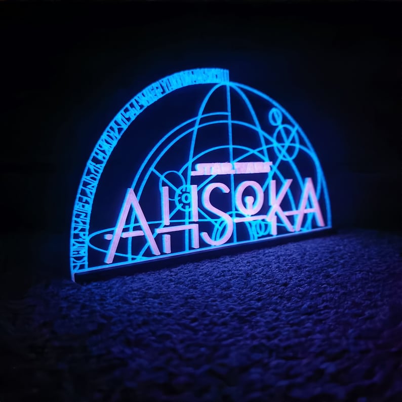 May include: A blue and pink neon sign with the text "STAR WARS" and "AHsoka" in a geometric design.