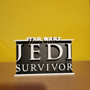 May include: A black and white 3D printed sign with the text "STAR WARS JEDI SURVIVOR".