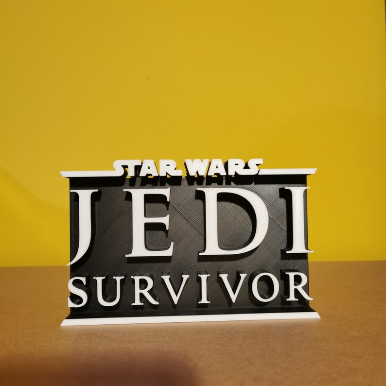 May include: A black and white 3D printed sign with the text "STAR WARS JEDI SURVIVOR".