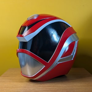 May include: A red and silver helmet with a black visor. The helmet has a white stripe around the top and a silver accent on the side.