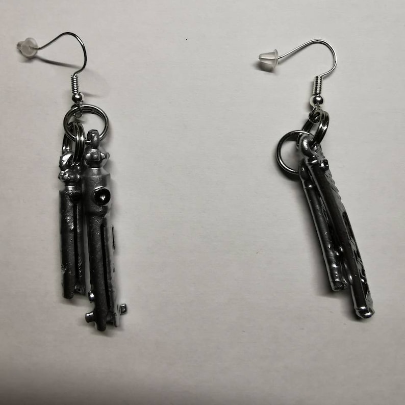 May include: A pair of silver earrings with a unique design. Each earring features a cluster of small, cylindrical shapes hanging from a silver hoop.