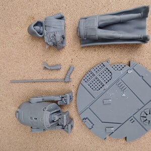 May include: A set of gray plastic miniature figures, including a hooded figure, a figure with a cape, a droid, and a base. The figures are for a tabletop game or role-playing game.