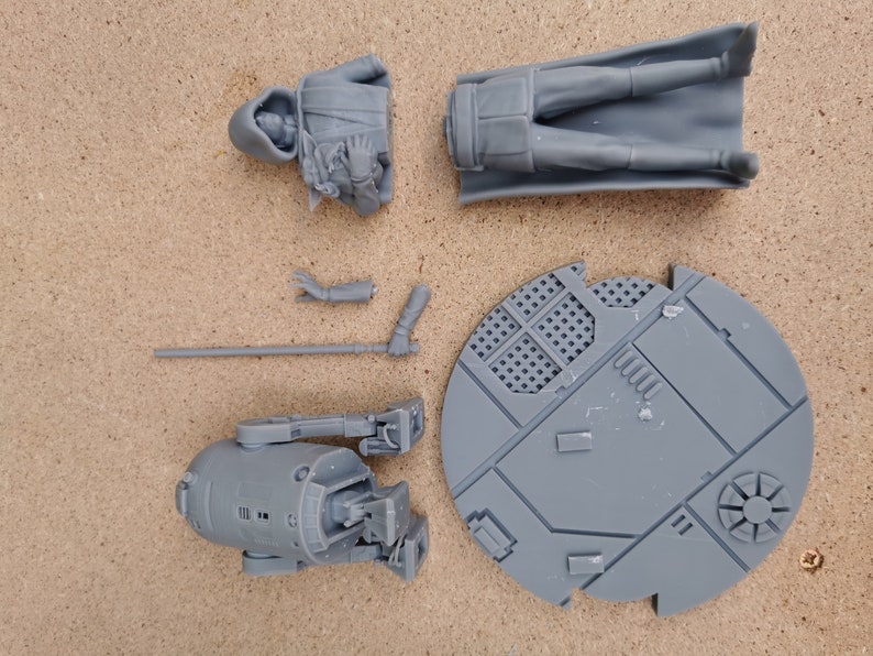 May include: A set of gray plastic miniature figures, including a hooded figure, a figure with a cape, a droid, and a base. The figures are for a tabletop game or role-playing game.
