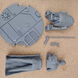 May include: A set of gray 3D printed Star Wars figures, including a droid, a character, and a base. The figures are unpainted and ready to be assembled.