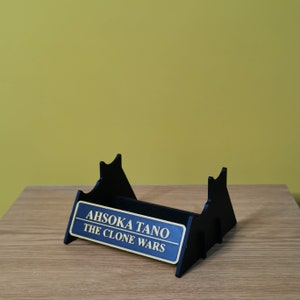 May include: Black acrylic display stand with a blue and gold plaque that reads "Ahsoka Tano The Clone Wars".