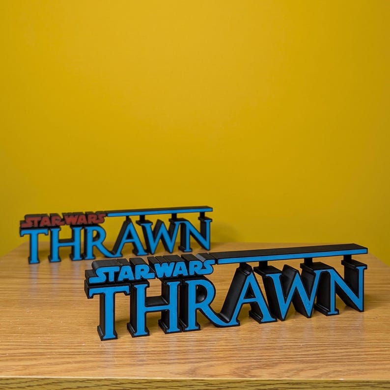 May include: Two 3D printed signs spelling "Thrawn" with the words "Star Wars" above each name. The top sign is red and black, and the bottom sign is blue and black.