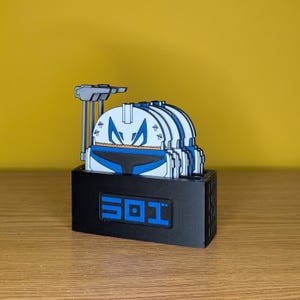 May include: A black display stand holding several white, blue, and black helmet-shaped objects. The stand has the number "501" in blue. The background is yellow.