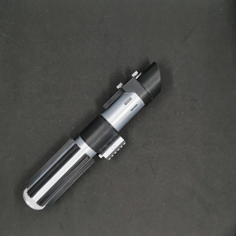 May include: A black and silver lightsaber toy with a textured handle and a black blade.