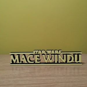 May include: A black and yellow 3D printed sign that reads "STAR WARS MACE WINDU".