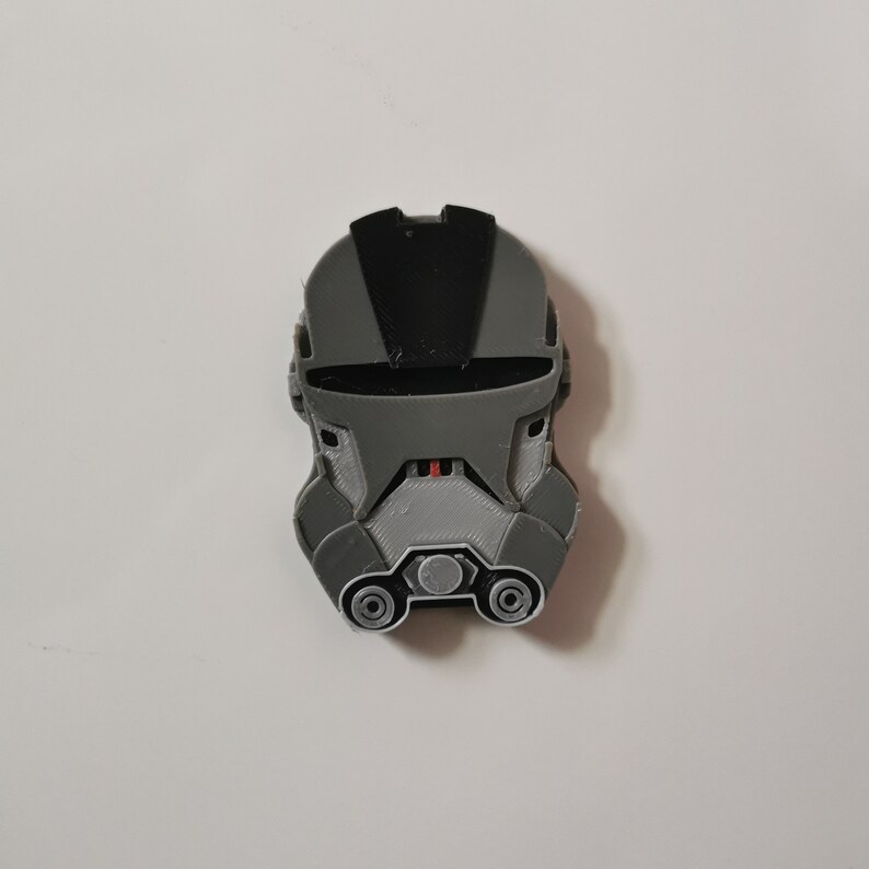 May include: A gray and black 3D printed helmet with a visor and a textured surface.