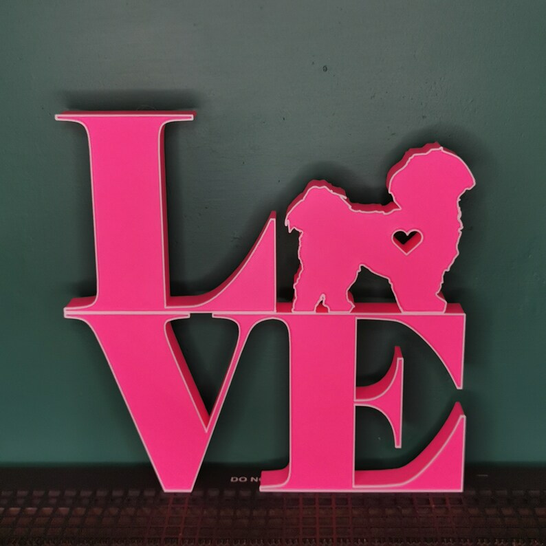 May include: Pink wooden "LOVE" sign with a white silhouette of a dog in the center of the "O". The dog has a small heart on its chest.