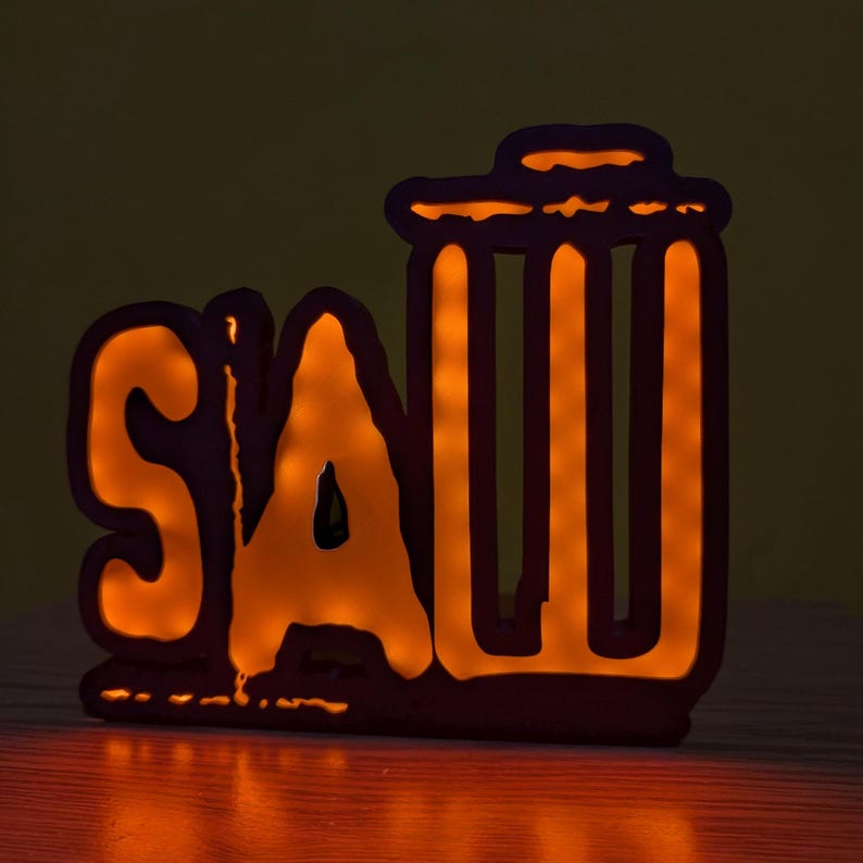May include: A lit-up sign with the word "SAW" and a trash can silhouette. The sign is made of a dark material and has a warm orange glow.