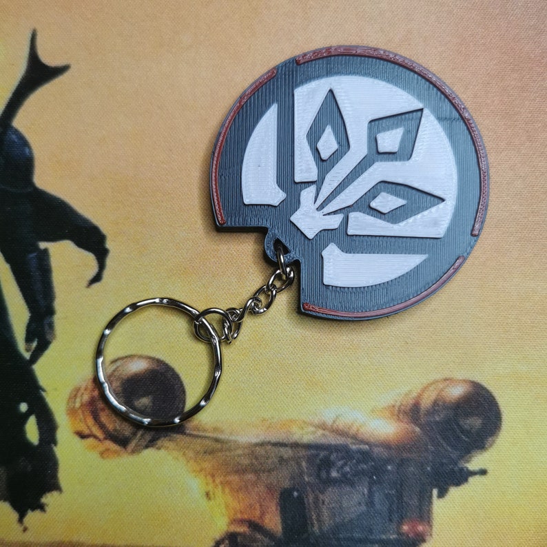 May include: A black and white keychain featuring a stylised design of a flower with three petals. The keychain is attached to a silver metal ring and chain.