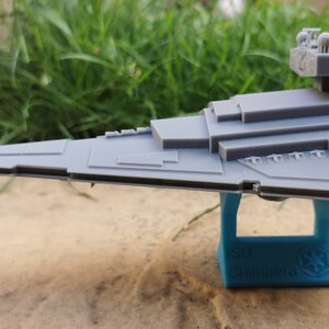 May include: A gray plastic model of a Star Destroyer spaceship on a blue stand with the text "Star Wars" printed on it.