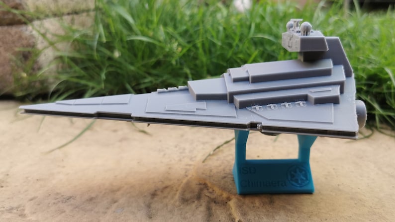 May include: A gray plastic model of a Star Destroyer spaceship on a blue stand with the text "Star Wars" printed on it.