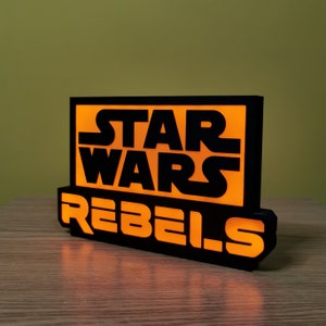 May include: A black and orange light-up sign with the text "Star Wars Rebels".