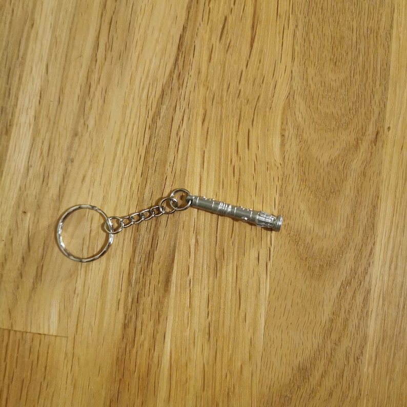 Op de afbeelding: Een zilveren metalen sleutelhanger met een replica van de sonic screwdriver van de Doctor uit de populaire sciencefiction-televisieserie Doctor Who.