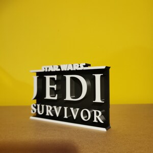 May include: A black and white 3D printed sign with the text "STAR WARS JEDI SURVIVOR".