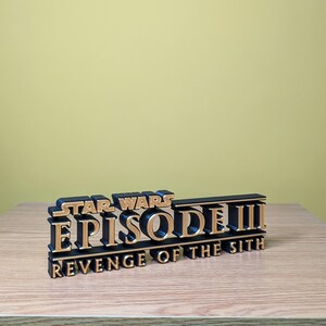 May include: A black and gold 3D printed replica of the Star Wars Episode III: Revenge of the Sith movie title.