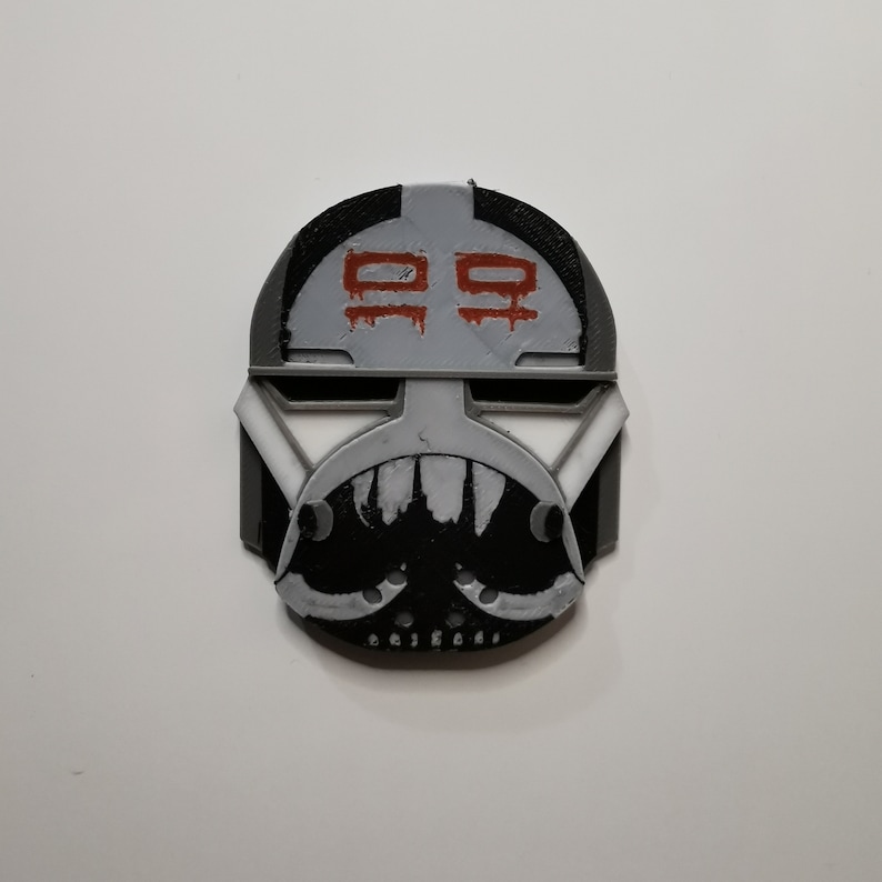 May include: A 3D printed black and white helmet with a red and white symbol on the front. The symbol is a stylized "99".