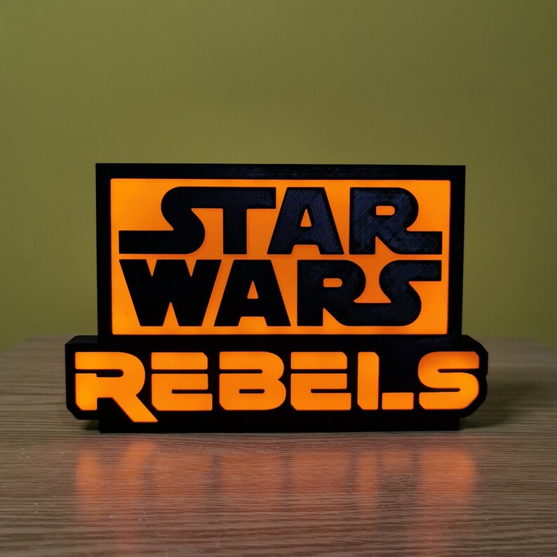 May include: A black and orange sign with the text "Star Wars Rebels" in a bold, blocky font.