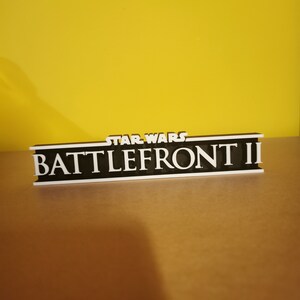 May include: A black and white 3D printed sign with the text "STAR WARS BATTLEFRONT II" in white letters.