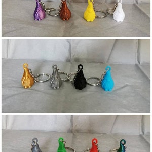 May include: A set of 10 colourful gnome keychain ornaments. The gnomes are made of plastic and have a variety of colours, including purple, brown, yellow, white, gold, silver, black, blue, green, and red. Each gnome has a small beard and a pointy hat.