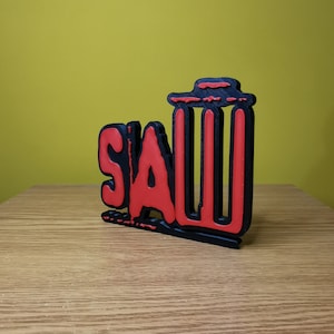 May include: A black and red 3D printed sign that says "SAW" with a trash can icon next to it.