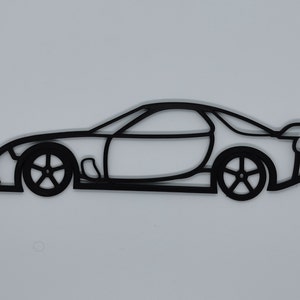May include: A black line drawing of a sports car, viewed from the side. The car has a rounded body style with a low profile and a large rear spoiler.