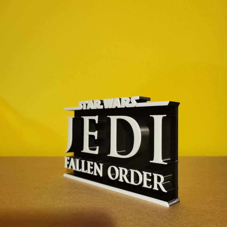 May include: A black and white 3D printed sign with the text "Star Wars Jedi Fallen Order".