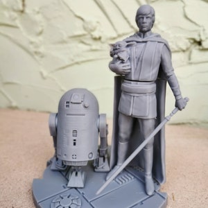May include: A gray 3D printed figurine set featuring Luke Skywalker holding a small Yoda figure, R2-D2, and a lightsaber. The figures are standing on a circular base with a textured surface.
