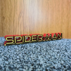 May include: A red and gold 3D plastic sign that reads "SPIDER-MAN".