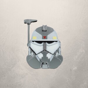 May include: A gray and white plastic helmet with a red triangle and yellow accents. The helmet has a visor and a small antenna on top.