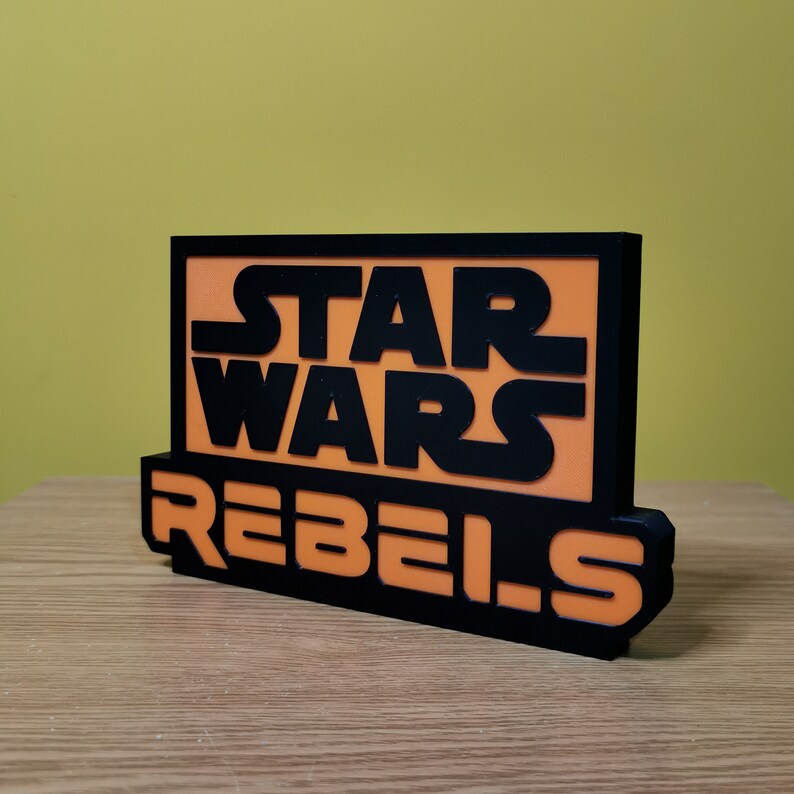 May include: Black and orange sign with the text "Star Wars Rebels" in a bold, blocky font.