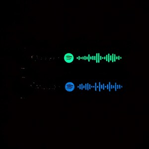 May include: Two Spotify music codes, one green and one blue, on a black background. The codes are for two different songs.