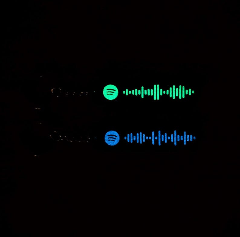 May include: Two Spotify music codes, one green and one blue, on a black background. The codes are for two different songs.