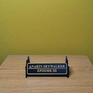 May include: A black display stand with a gold plaque that reads "Anakin Skywalker Episode III".