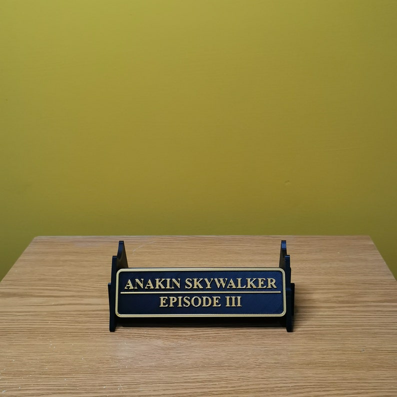 May include: A black display stand with a gold plaque that reads "Anakin Skywalker Episode III".