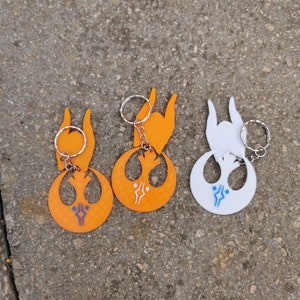 Pu&ograve; includere: Tre portachiavi con il simbolo dell'Alleanza Ribelle di Star Wars. Due sono arancioni e uno &egrave; bianco. Ogni portachiavi ha un anello argentato e un piccolo design dettagliato.