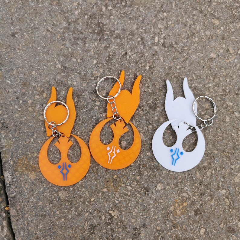 Pu&ograve; includere: Tre portachiavi con il simbolo dell'Alleanza Ribelle di Star Wars. Due sono arancioni e uno &egrave; bianco. Ogni portachiavi ha un anello argentato e un piccolo design dettagliato.