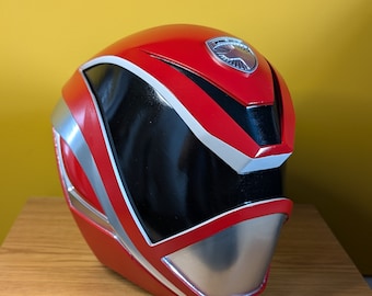 May include: Red and silver Power Ranger helmet with a black visor and a silver emblem on the top.