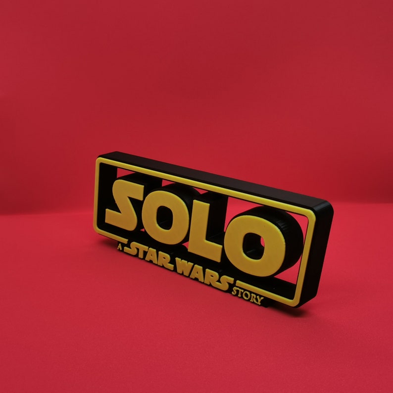 May include: Black and yellow 3D printed sign with the text "SOLO: A STAR WARS STORY".