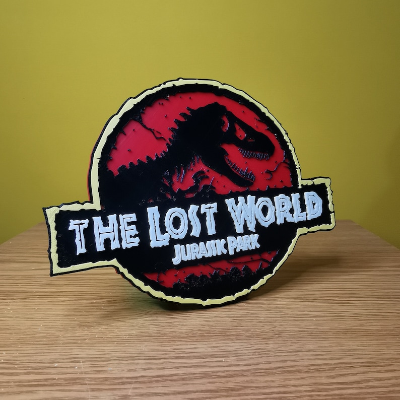 May include: A red, black, and yellow 3D printed sign with the text "The Lost World Jurassic Park" and a silhouette of a dinosaur.