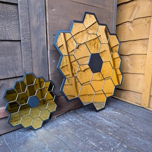 May include: Two black framed mirrors with gold hexagonal tiles. The larger mirror is about 18 inches in diameter and the smaller mirror is about 10 inches in diameter.